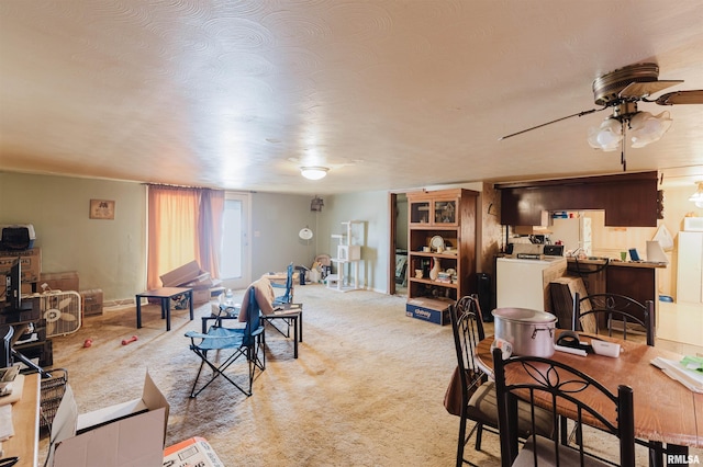 carpeted living area with washer / dryer and a ceiling fan