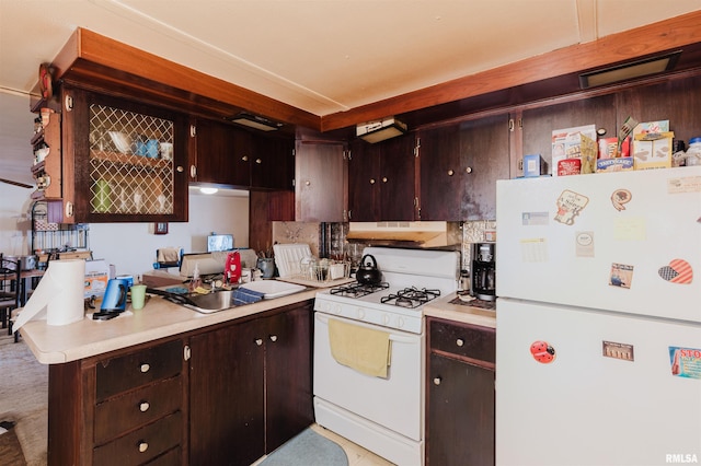 kitchen with under cabinet range hood, white appliances, light countertops, and a sink