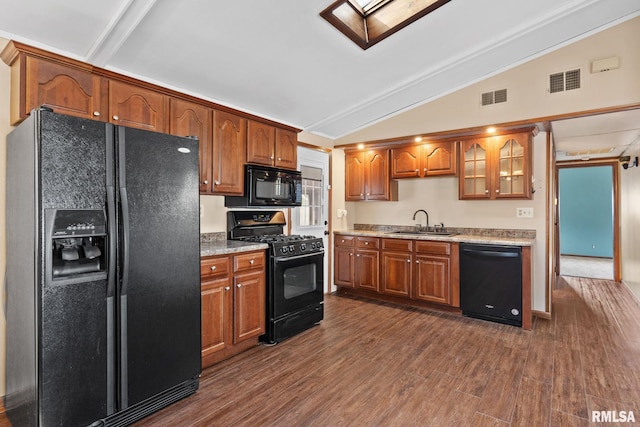 kitchen with a sink, visible vents, vaulted ceiling with skylight, and black appliances