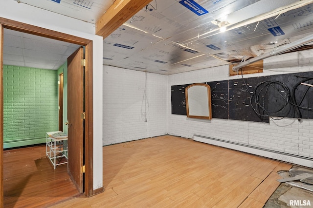 interior space with a baseboard heating unit, wood finished floors, and brick wall