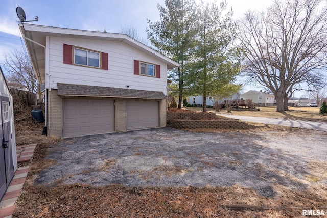 view of side of home with aphalt driveway, a garage, and brick siding