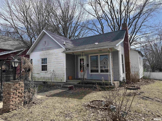 view of front of property with a porch, fence, and a chimney