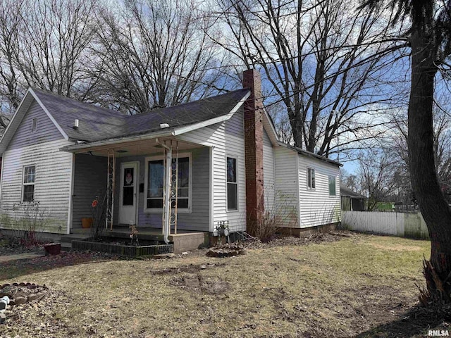 view of front of home with a shingled roof, a chimney, and fence