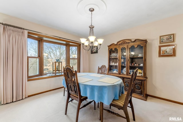 dining space featuring a notable chandelier, baseboards, and light colored carpet