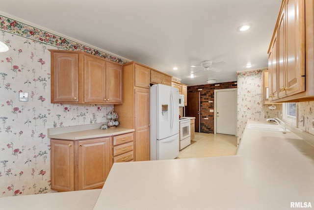 kitchen with a sink, white appliances, and wallpapered walls