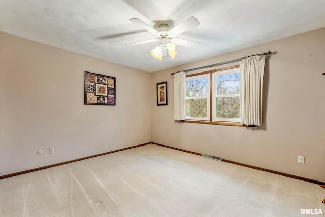 carpeted spare room featuring visible vents, a ceiling fan, and baseboards