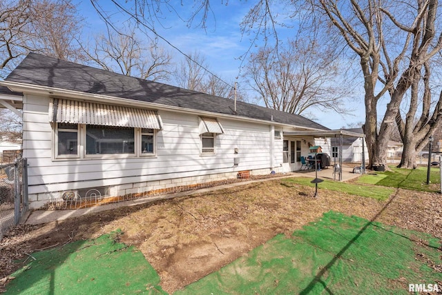 rear view of property featuring fence, a shingled roof, a patio area, crawl space, and a lawn