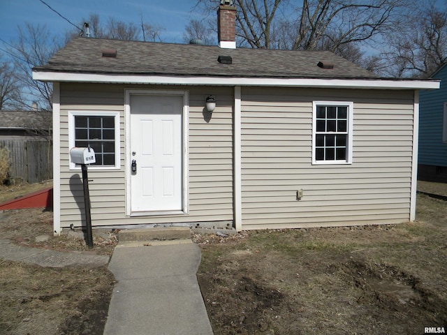 doorway to property with a chimney and a shingled roof