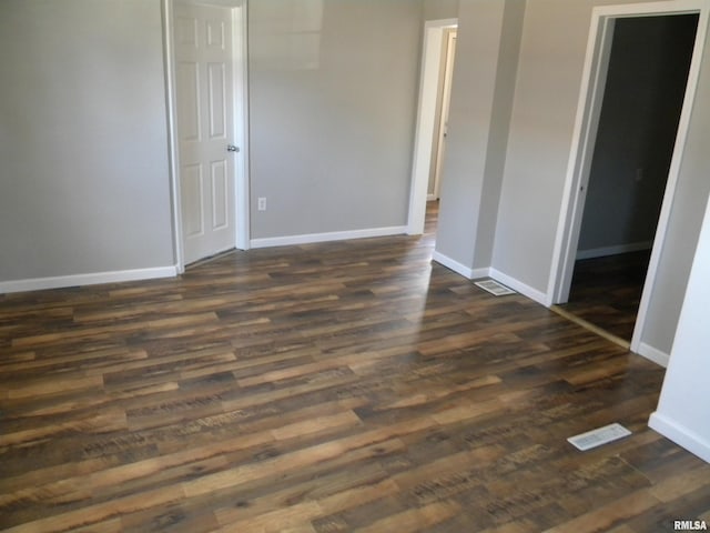 unfurnished room featuring visible vents, baseboards, and dark wood-style flooring