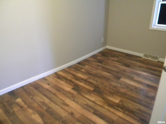 unfurnished room with dark wood-style floors, visible vents, and baseboards