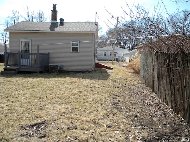 rear view of house with fence, a lawn, cooling unit, a chimney, and a deck