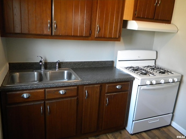 kitchen featuring dark countertops, a sink, ventilation hood, white gas range, and dark wood-style flooring