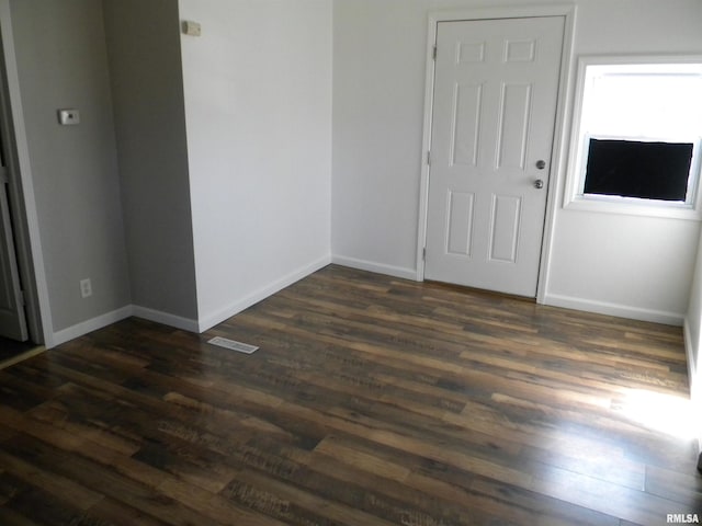 empty room with visible vents, baseboards, and dark wood-style flooring