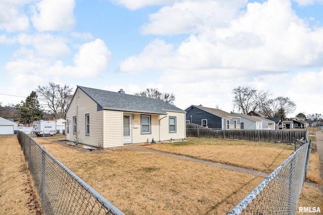 view of front of house with a front lawn, a fenced backyard, a residential view, and roof with shingles