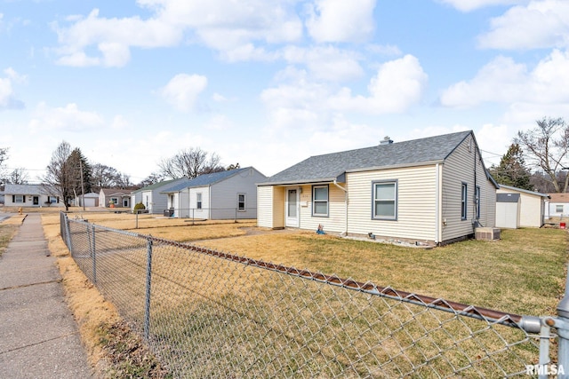 view of front of home featuring a front yard, fence, a residential view, and roof with shingles