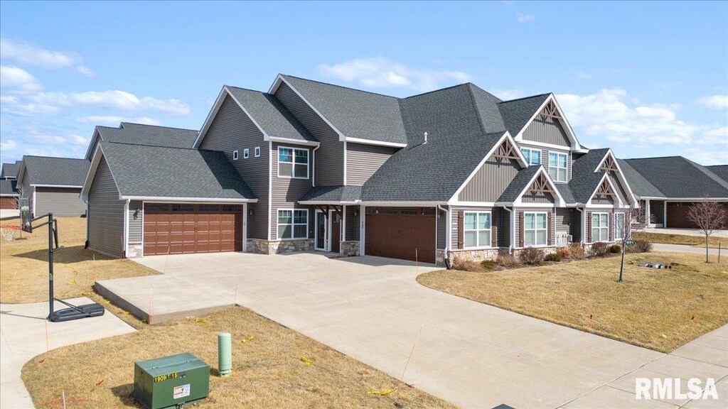 craftsman inspired home with stone siding, an attached garage, concrete driveway, a front yard, and roof with shingles