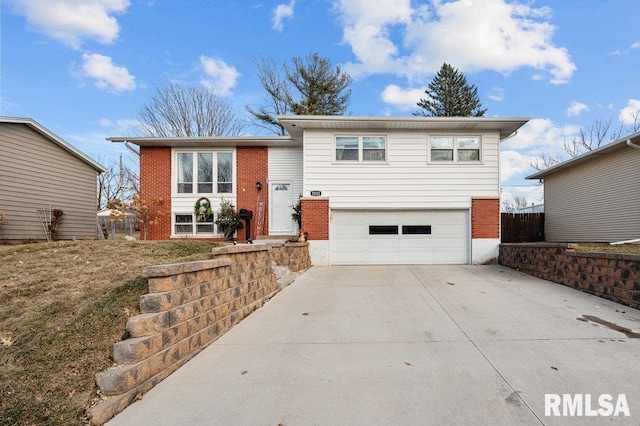 split foyer home featuring concrete driveway, a garage, and brick siding