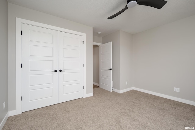 unfurnished bedroom with a closet, baseboards, a ceiling fan, and carpet flooring