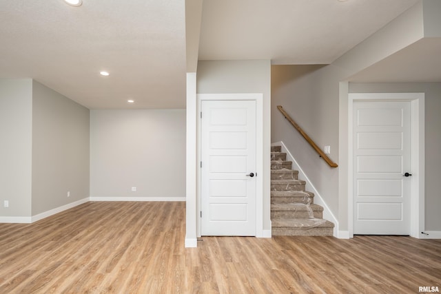 below grade area featuring stairs, recessed lighting, baseboards, and light wood finished floors