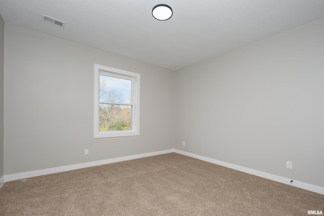 carpeted spare room featuring visible vents and baseboards