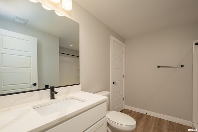 bathroom featuring vanity, wood finished floors, visible vents, baseboards, and toilet