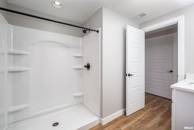 full bathroom featuring visible vents, wood finished floors, a shower, baseboards, and vanity