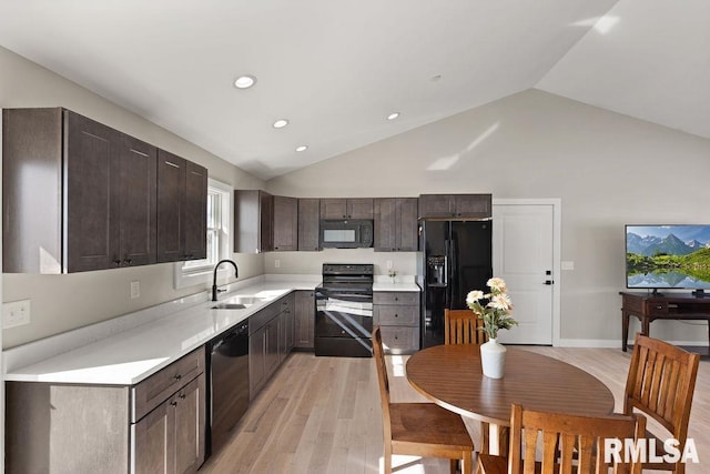 kitchen featuring black appliances, a sink, light wood finished floors, dark brown cabinets, and light countertops