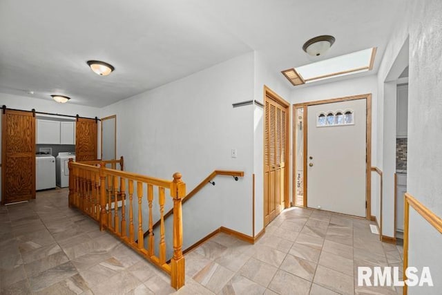 foyer featuring a barn door, baseboards, and washing machine and clothes dryer