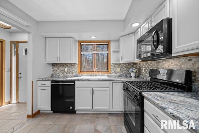 kitchen with light stone countertops, a sink, decorative backsplash, black appliances, and white cabinetry