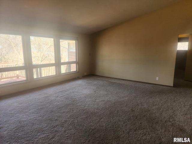 carpeted empty room featuring baseboards and vaulted ceiling