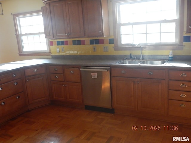 kitchen featuring a sink, stainless steel dishwasher, dark countertops, brown cabinetry, and decorative backsplash