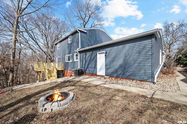 view of side of home with stairs, an outdoor fire pit, central air condition unit, and a wooden deck