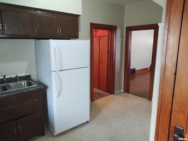 kitchen featuring dark brown cabinetry, visible vents, freestanding refrigerator, and a sink