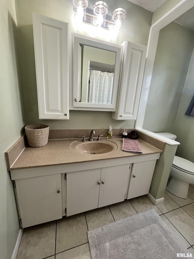 bathroom featuring vanity, toilet, baseboards, and tile patterned flooring