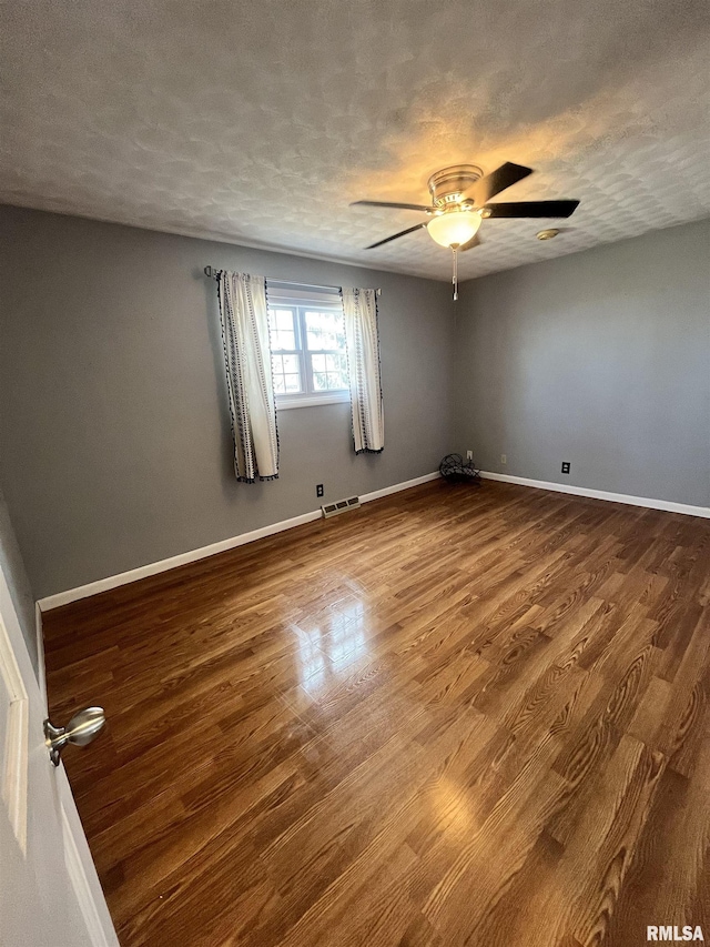 empty room with dark wood finished floors, visible vents, and a textured ceiling