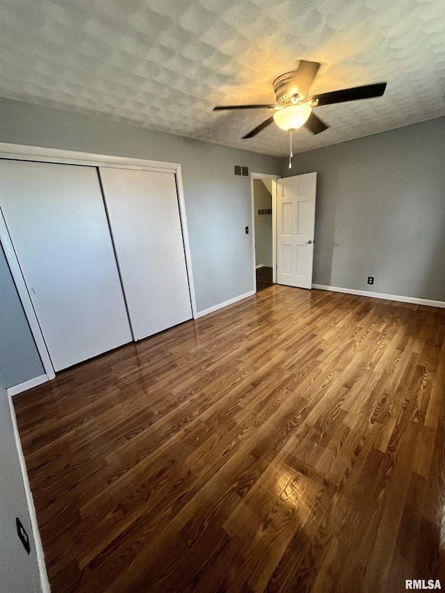 unfurnished bedroom with visible vents, baseboards, wood finished floors, a closet, and a textured ceiling