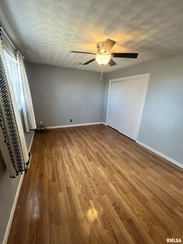 unfurnished bedroom with baseboards, a textured ceiling, wood finished floors, and a ceiling fan