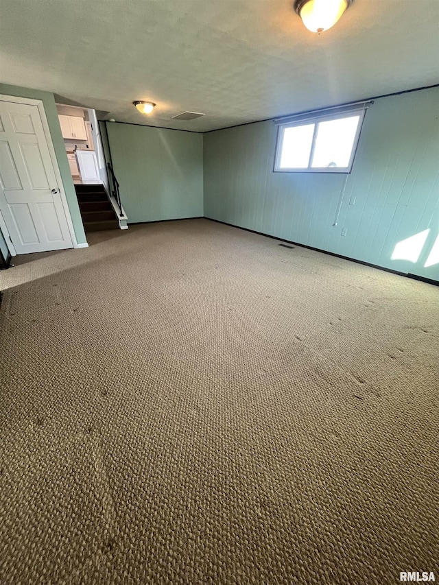 empty room with stairway, visible vents, and dark colored carpet