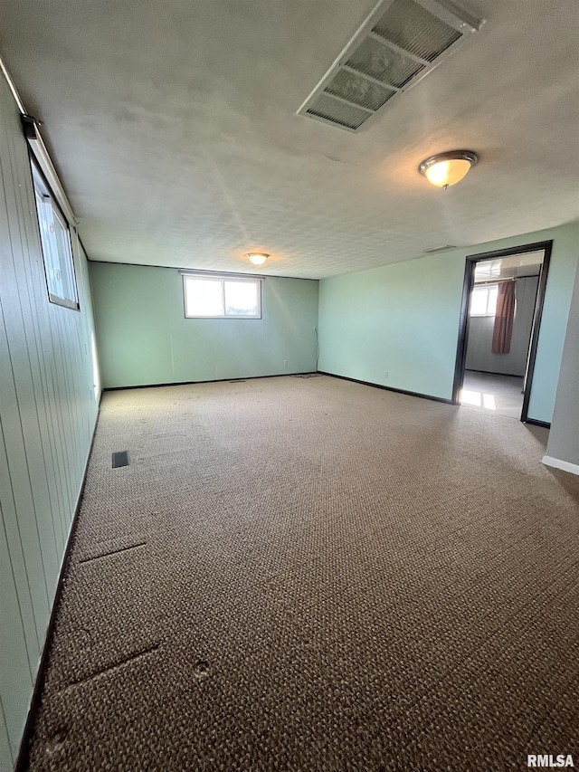 spare room featuring a wealth of natural light, visible vents, and carpet