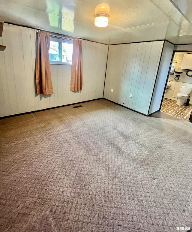 unfurnished bedroom featuring ensuite bath, carpet flooring, and visible vents