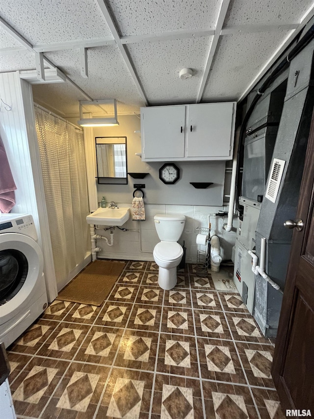 bathroom with toilet, washer / clothes dryer, a paneled ceiling, and a sink