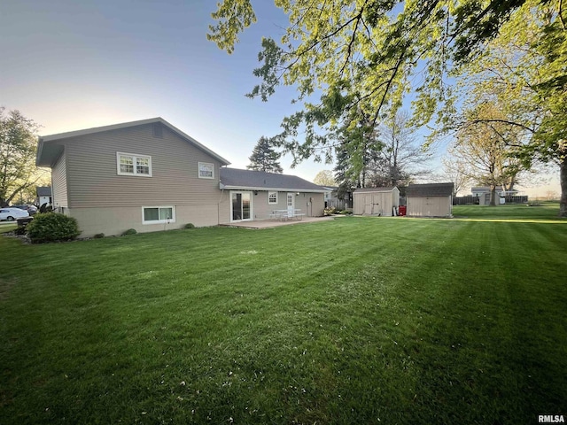 rear view of property with a yard, a storage shed, an outdoor structure, and a patio area