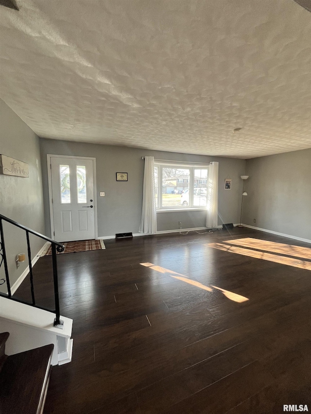 foyer with stairway, a textured ceiling, baseboards, and wood-type flooring