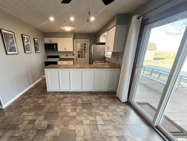 kitchen featuring baseboards, ceiling fan, a sink, white cabinets, and appliances with stainless steel finishes