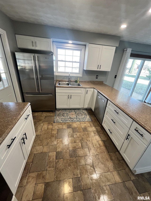 kitchen with a sink, white cabinetry, a wealth of natural light, and stainless steel appliances