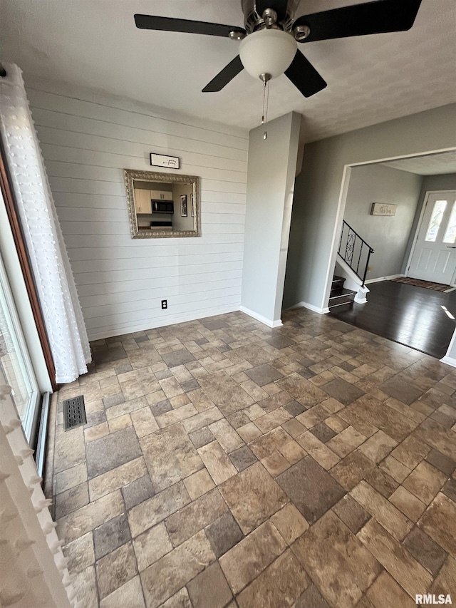 exterior space with stairway, baseboards, visible vents, stone finish floor, and wood walls