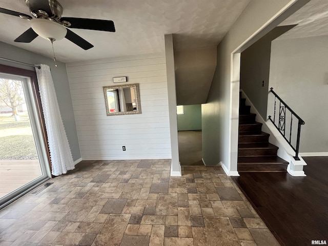 interior space featuring wooden walls, stone finish flooring, and baseboards