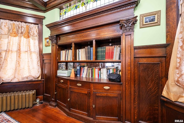 details featuring wood finished floors, radiator heating unit, ornamental molding, wainscoting, and a decorative wall