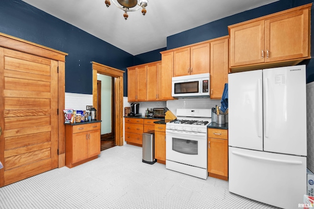 kitchen with backsplash, white appliances, and dark countertops