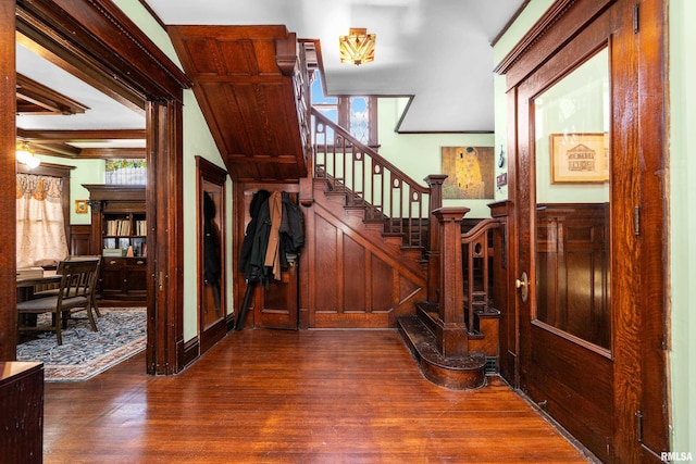 staircase with wood finished floors and wainscoting